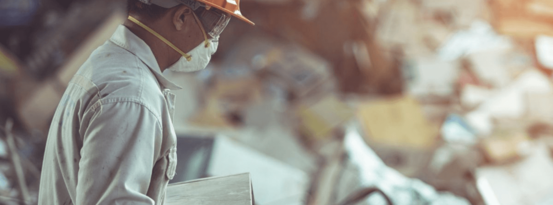 Man in full PPE sorting through e-waste and WEEE at a waste facility